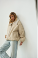 A short milk-colored bomber jacket made of natural sheepskin