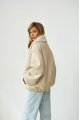 A short milk-colored bomber jacket made of natural sheepskin