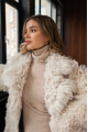 A long two-sided sheepskin coat made of milk-colored natural sheepskin